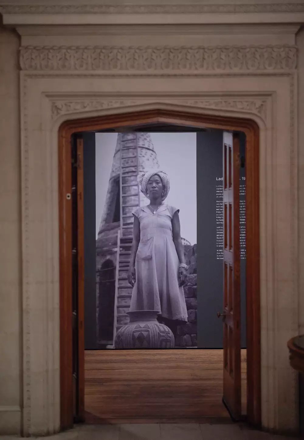 Archival photograph of Ladi Kwali on view in Body Vessel Clay: Black Women, Ceramics & Contemporary Art, Two Temple Place, London (29 January–24 April 2022). © Two Temple Place. Courtesy Two Temple Place. Photo: Amit Lennon Archival photograph of Ladi Kwali, printed out large scale on the wall, framed by a doorway entrance to the room