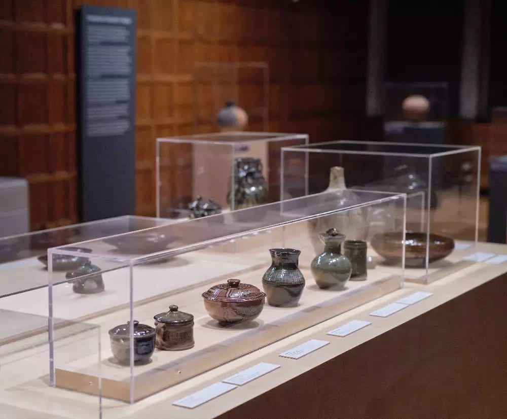 Exhibition view: Body Vessel Clay: Black Women, Ceramics & Contemporary Art, Two Temple Place, London (29 January–24 April 2022). © Two Temple Place. Courtesy Two Temple Place. Photo: Amit Lennon A selection of small pots in a large glass cabinet at table hight
