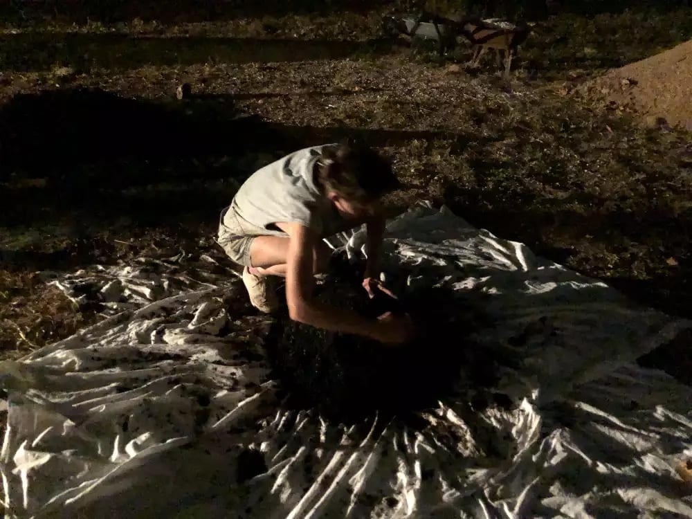 The artist preparing to roll a ball of sand in a large cloth