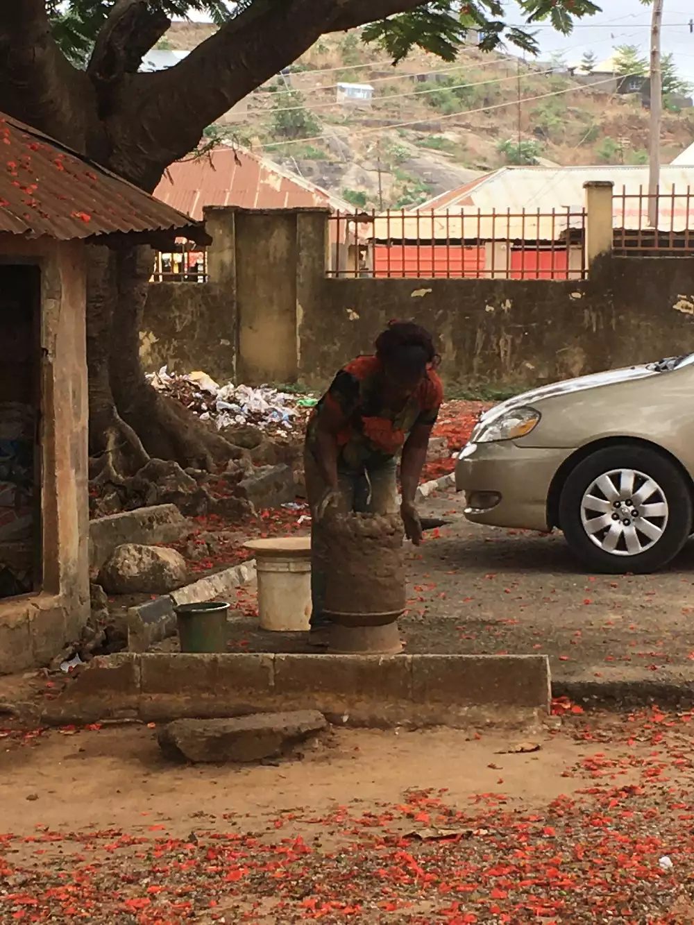 Research trip Ushafa Pottery, Abuja, Nigeria, May 2021, (c) Jareh Das An outdoor scene with a person working with clay next to the road