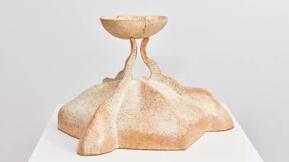 A sculpture made from glazed ceramic, the sculpture is holding up a skull (kapala) made in a cast resin